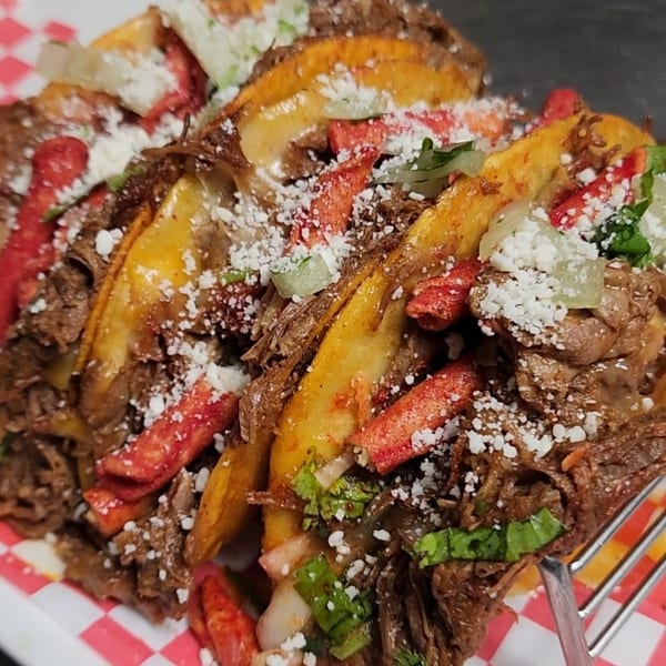 Close-up of three El Paso Mexican Restaurant tacos filled with meat, cheese, and red chips.