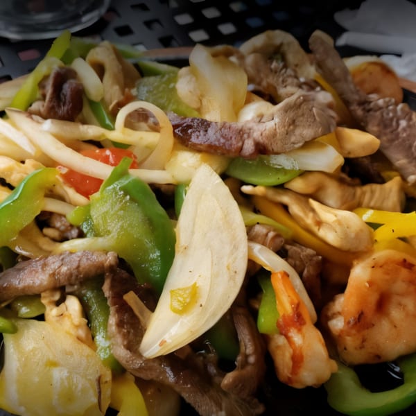 Close-up of El Paso Mexican Restaurant's sizzling fajitas with beef, shrimp, onions, and bell peppers.